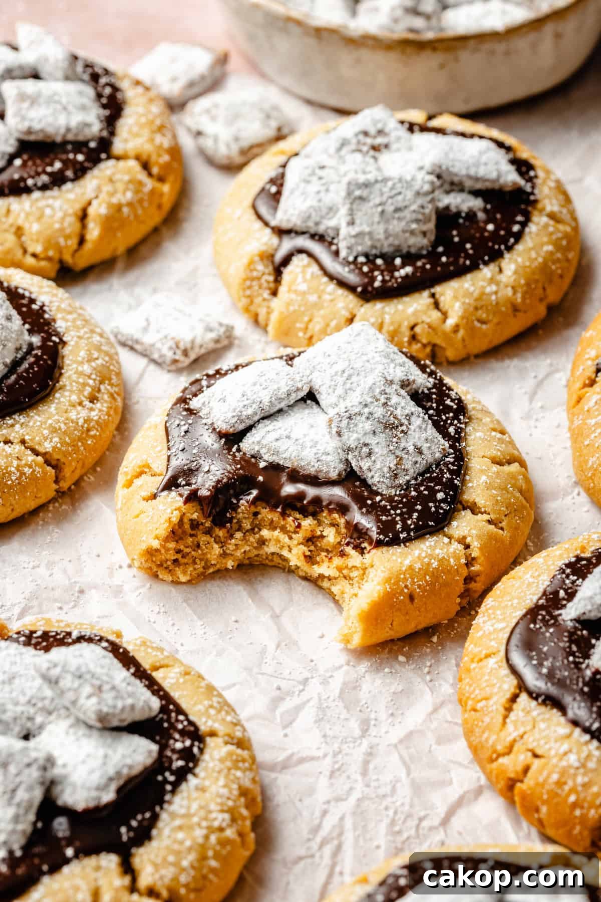 Chocolate Puppy Chow Cookies Recipe for Parties and Gifts 9 a bite taken out of a soft puppy chow peanut butter cookie topped with ganache and muddy buddys