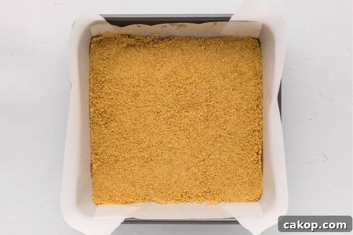 Cheesecake Bars with Graham Cracker Crust Graham cracker crust pressed into 8x8 baking pan lined with parchment paper.