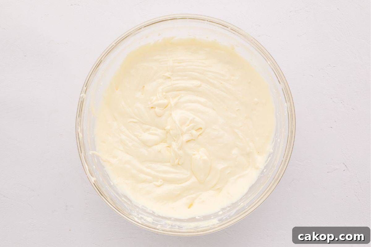 Creamy Lemon Cheesecake Bars Cream cheese, sour cream, eggs, and lemon mixed together in mixing bowl.