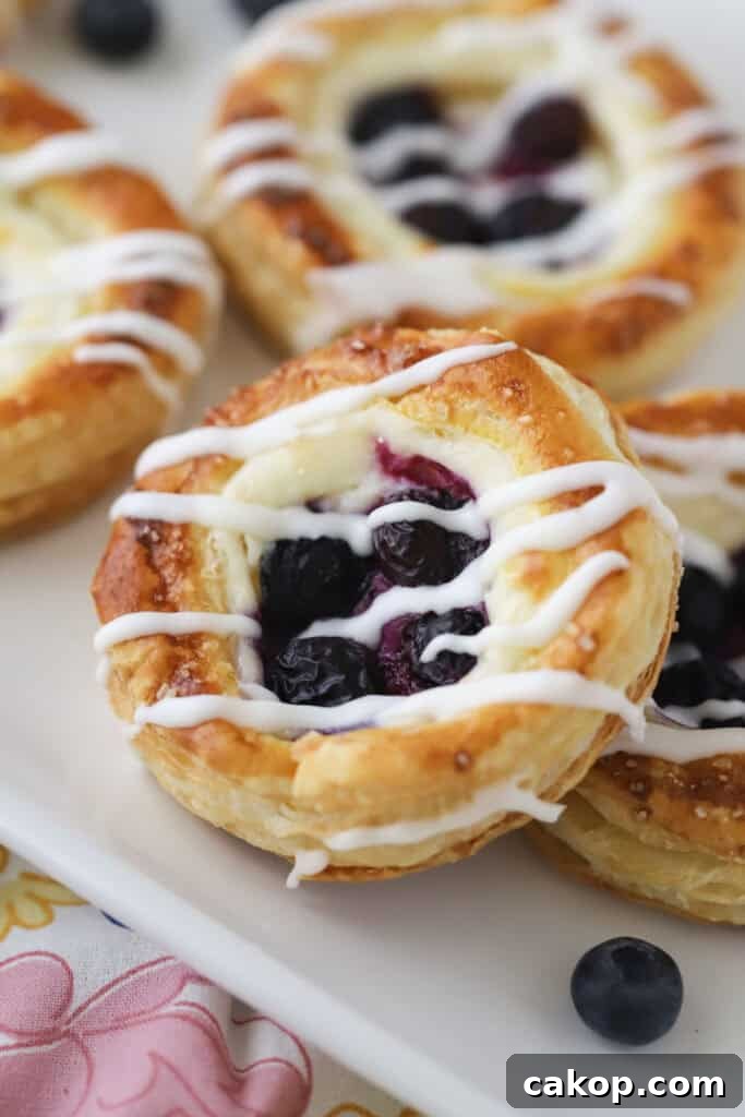 A plate full of blueberry danish topped with homemade glaze.