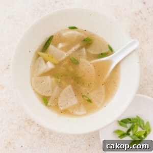 a bowl of mu guk next to a plate of freshly sliced green onions
