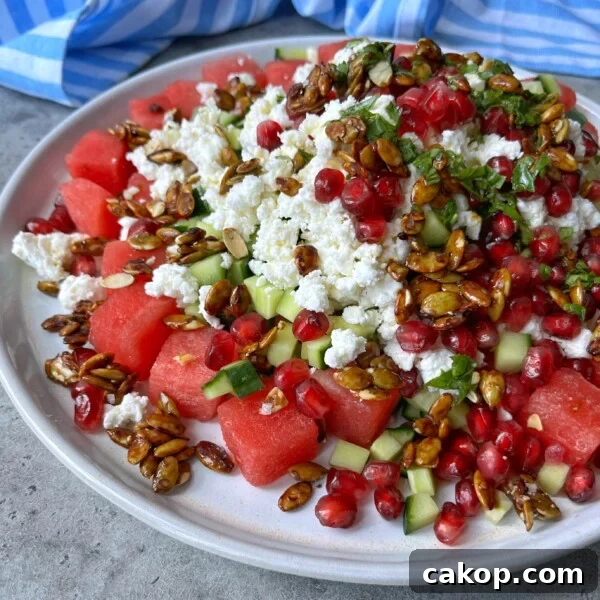 A plate of fresh watermelon, cucumber, and crumbled feta topped with pomegranate seeds, chopped herbs, and caramelized sunflower seeds makes for one of the most refreshing health bites in summer food recipes.