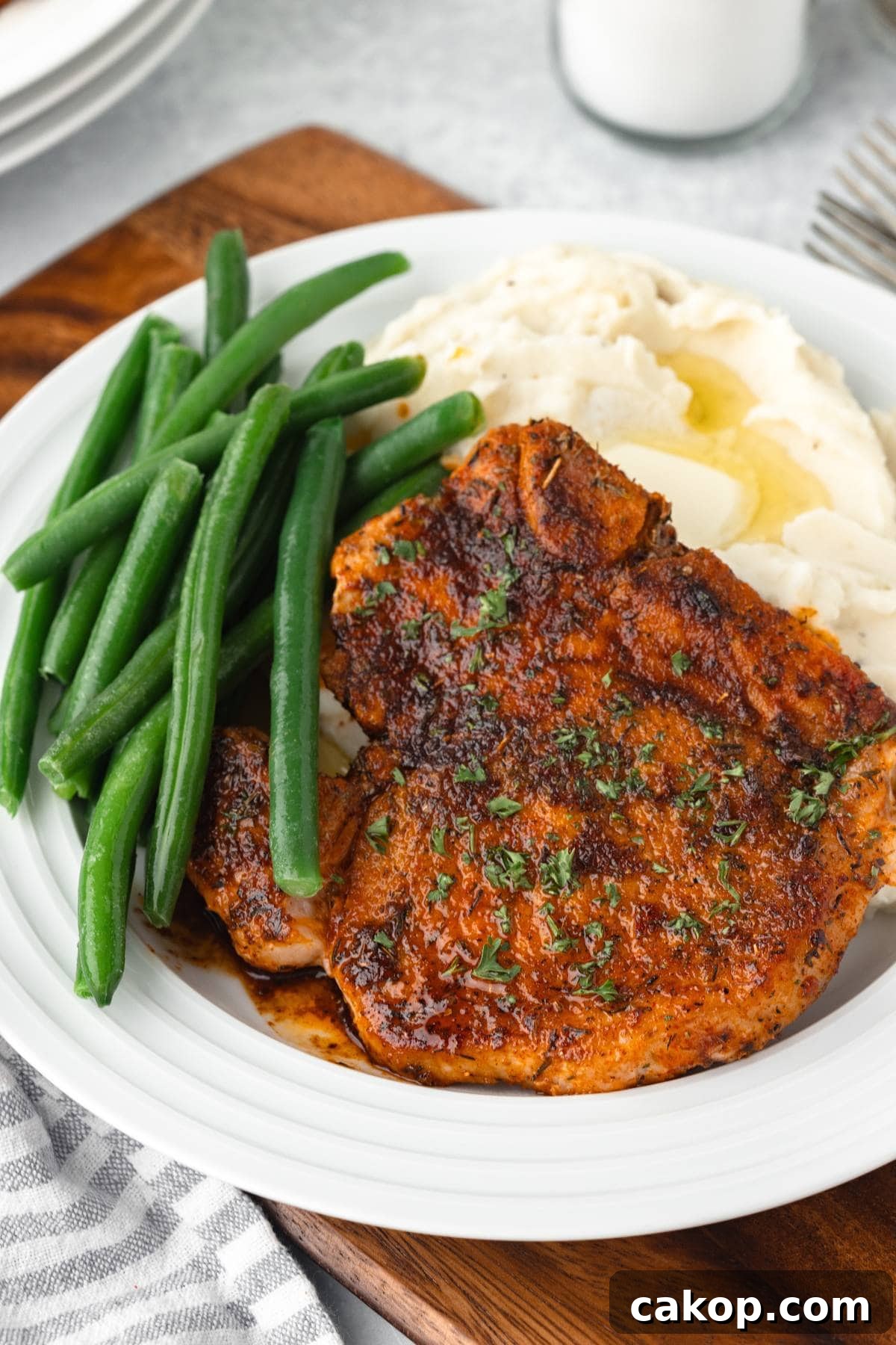 Juicy Bone-In Pork Chops: Simple Step-by-Step Cooking Guide 2 Bone-In Pork Chops with mashed potatoes and green beans on a white plate.