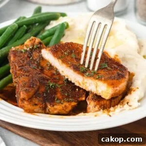 Juicy Bone-In Pork Chops: Simple Step-by-Step Cooking Guide 9 A cooked pork chop shown sliced in half with a fork in it.