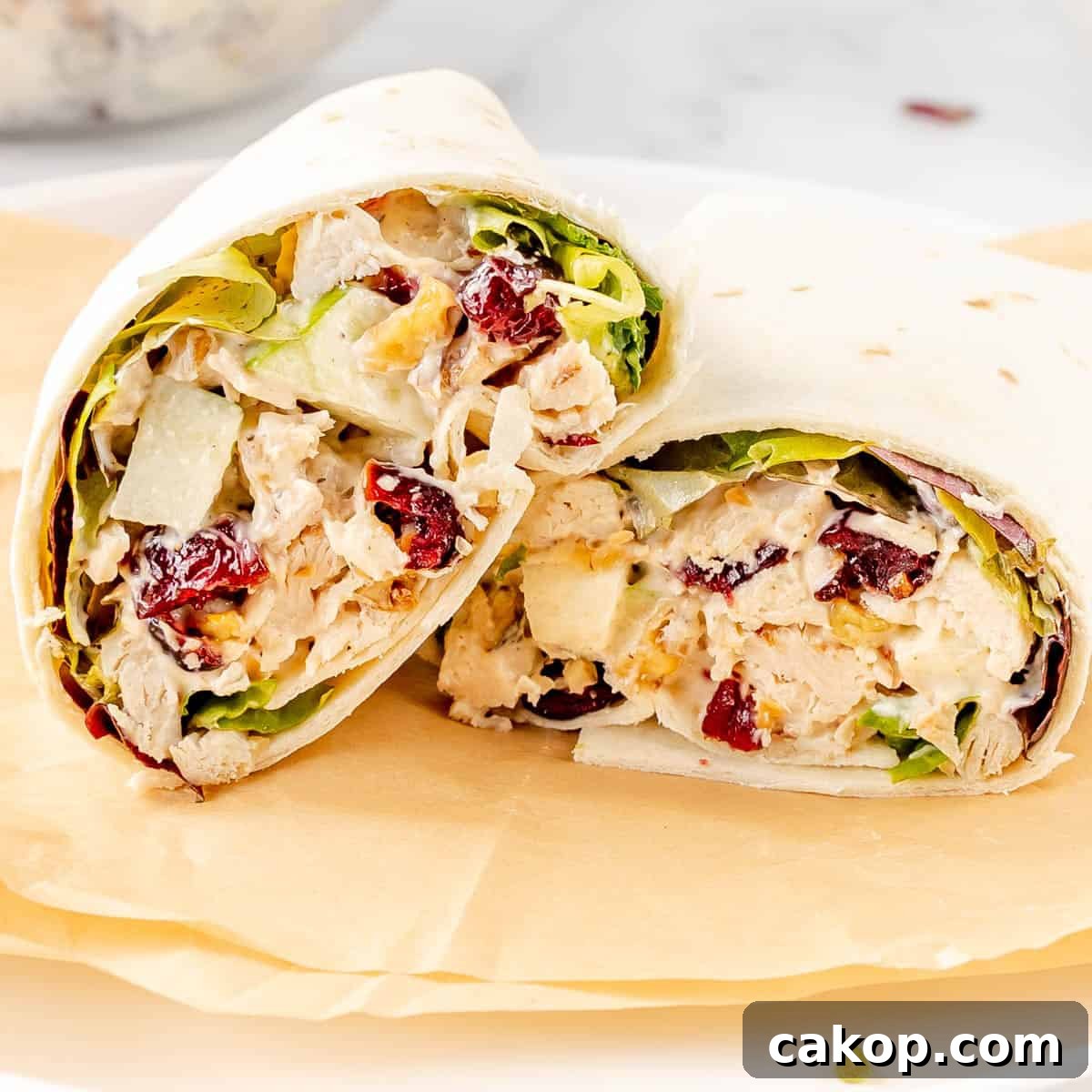 Classic Cape Cod Chicken Salad Recipe with Cranberries & Pecans 7 Chicken salad wrap with lettuce, cranberries, and nuts on parchment paper.