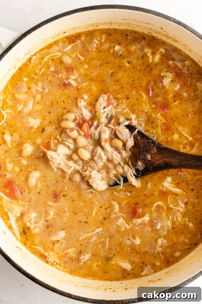 Southwest Chicken Chili: Spicy Crockpot Recipe for Weeknights 4 a pot of southwest chicken chili with a wooden spoon