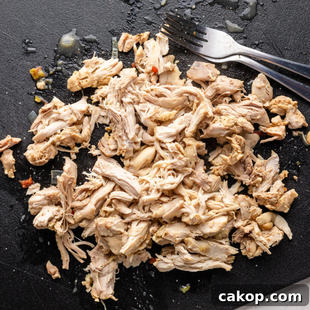 Southwest Chicken Chili: Spicy Crockpot Recipe for Weeknights 6 shredded chicken on a cutting board with two forks