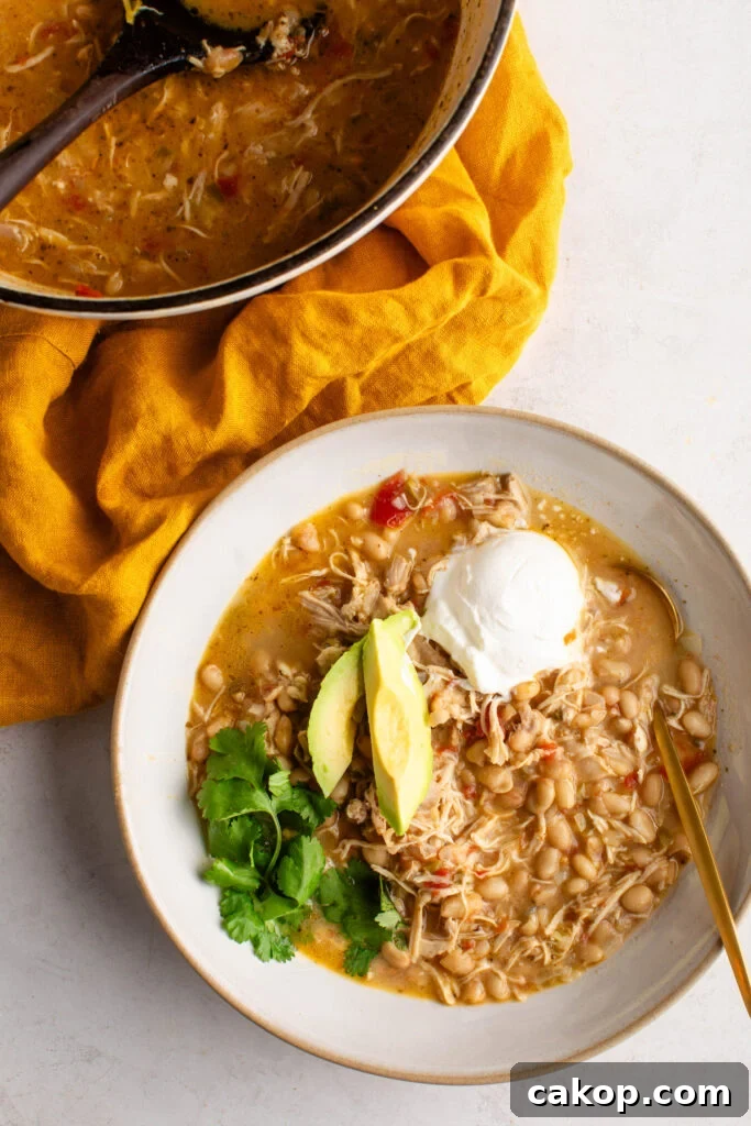 Southwest Chicken Chili: Spicy Crockpot Recipe for Weeknights 8 a bowl of southwest chicken chili topped with sour cream, avocado, and cilantro