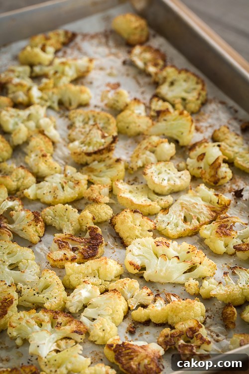 Crispy Roasted Cauliflower with Parmesan and Garlic 4 Golden roasted cauliflower florets on a sheet tray lined with parchment paper.