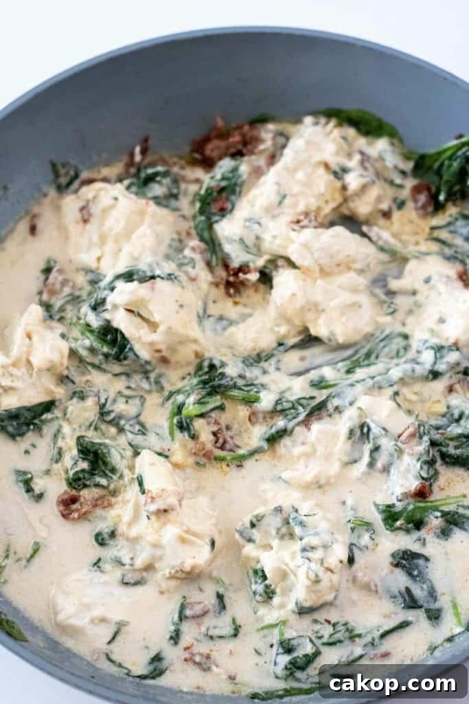 A pan of creamy spinach and artichoke dip with visible pieces of spinach and artichoke in a thick, white sauce, reminiscent of the rich flavors found in a bowl of Creamy Tuscan Pasta.