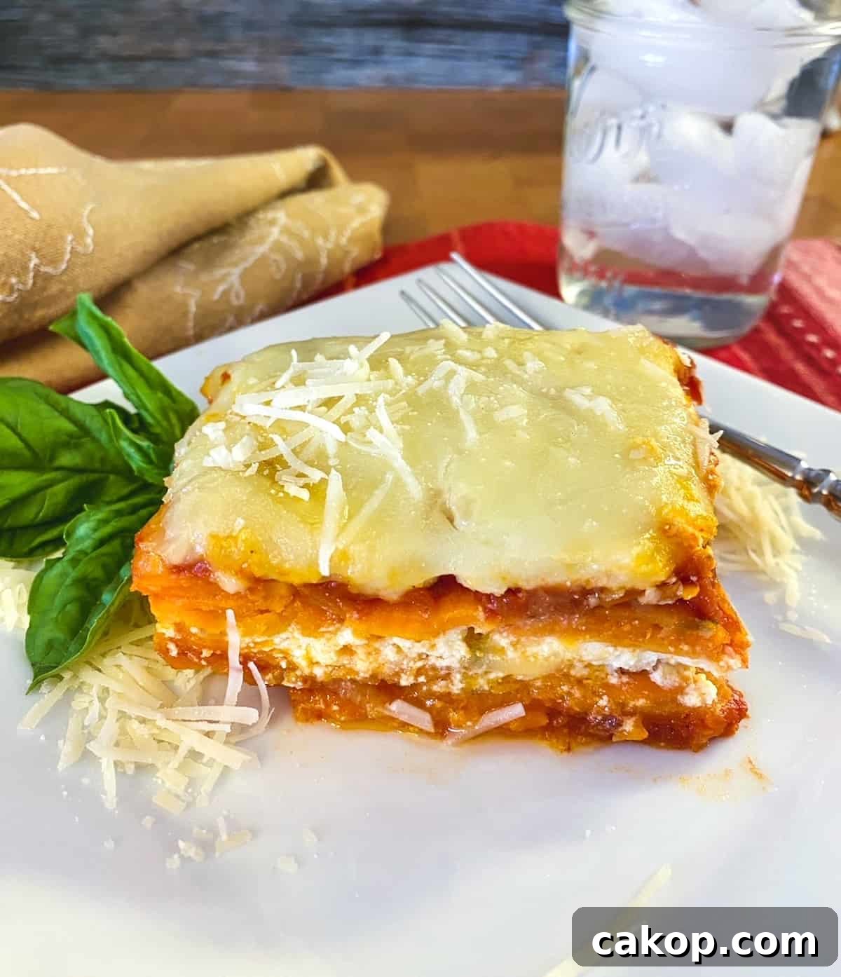 Sweet Potato Lasagna Recipe with Creamy Ricotta and Spinach 2 A serving of sweet potato lasagna on a plate with a glass of water off to the side.