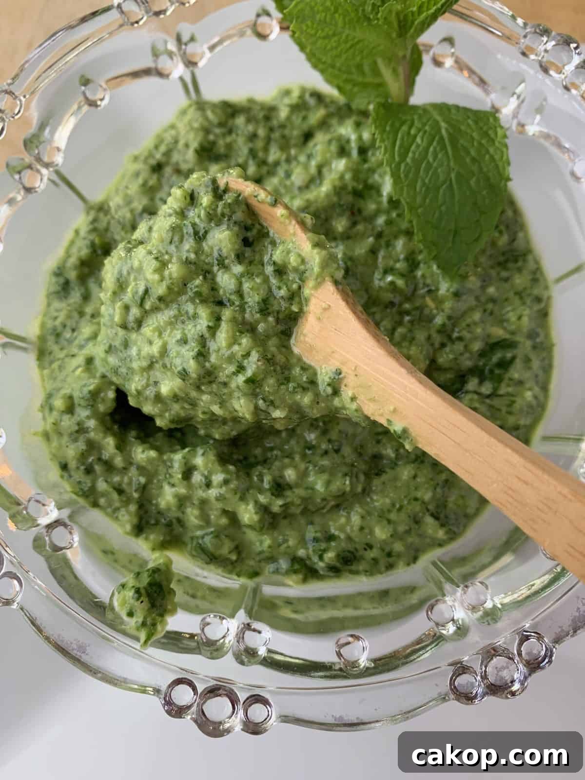 Pesto sauce in spoon over a bowl of pesto