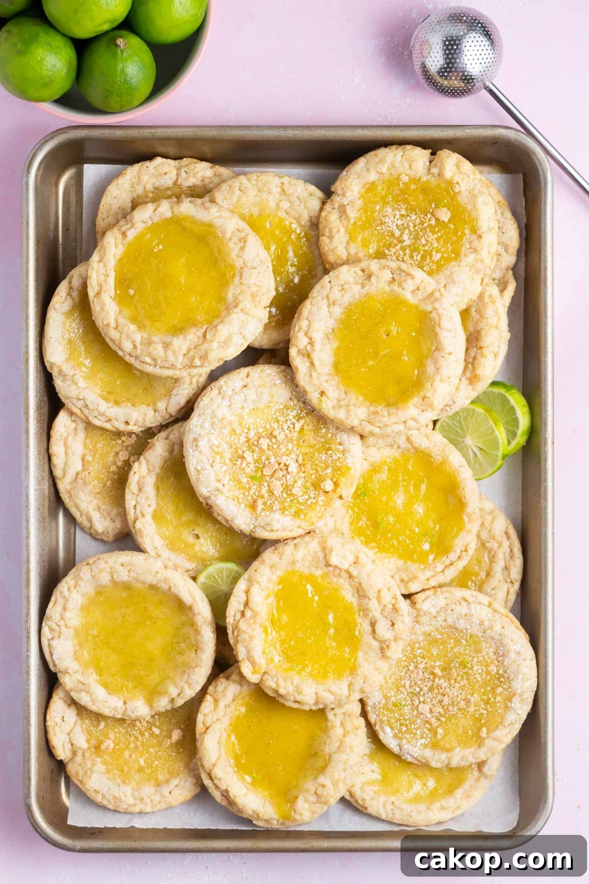 key lime cookies piled on a baking sheet with key limes
