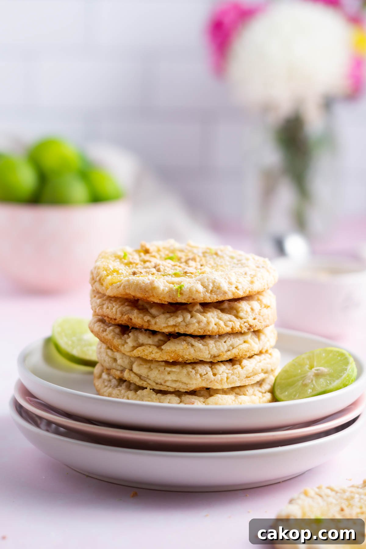 stack of cookies on a plate with a bowl of limes in the background