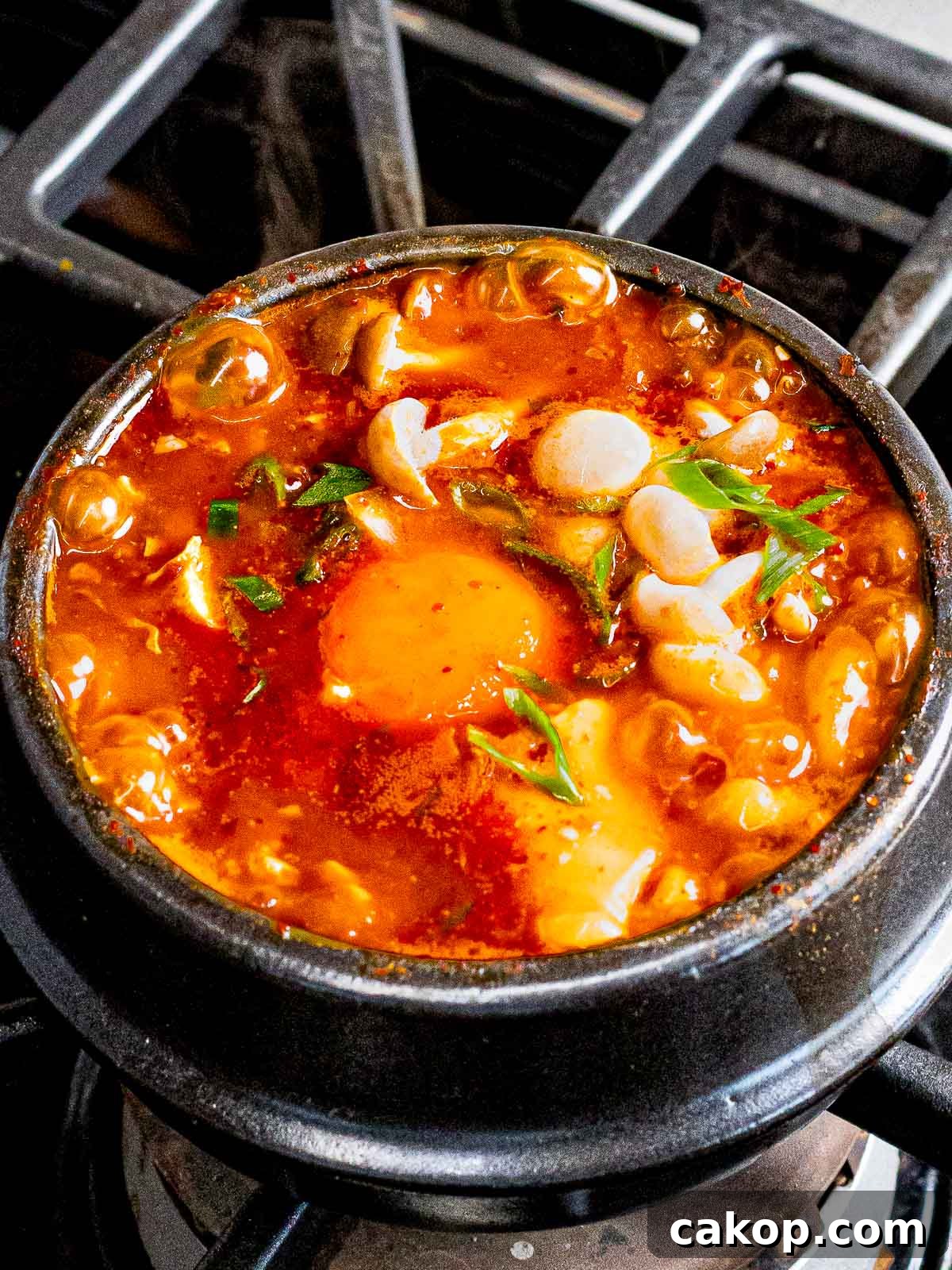 Spicy Korean Soondubu Jjigae (Silken Tofu Stew Recipe) 8 Soondubu jiggae (spicy Korean soft tofu soup) with mushrooms, egg, and green onions.