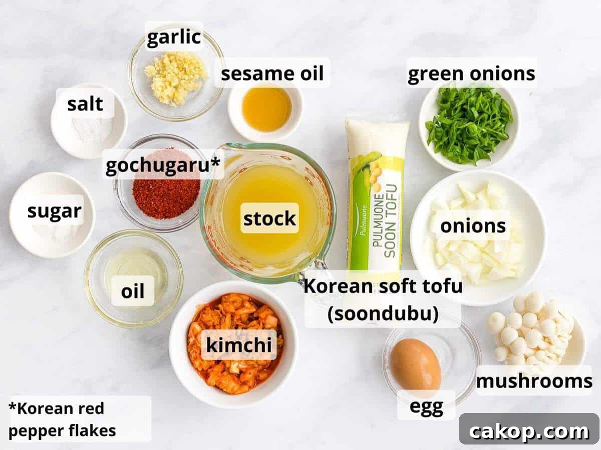 Spicy Korean Soondubu Jjigae (Silken Tofu Stew Recipe) 4 Ingredients for soondubu jiggae including soon tofu, broth, kimchi, and mushrooms.